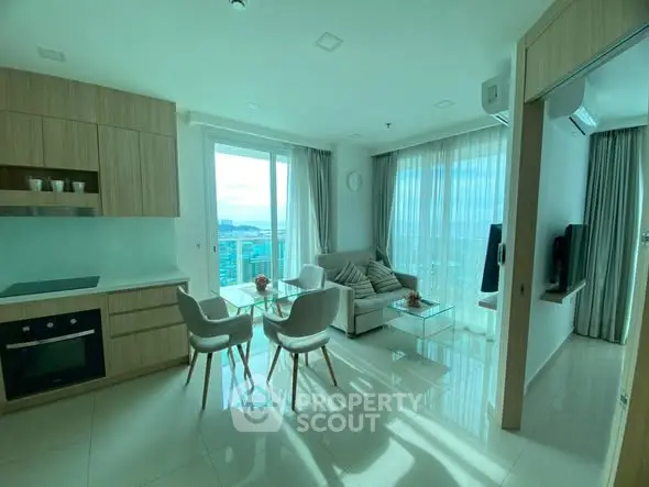Modern open-layout living room with kitchen, featuring ocean view and stylish furniture.