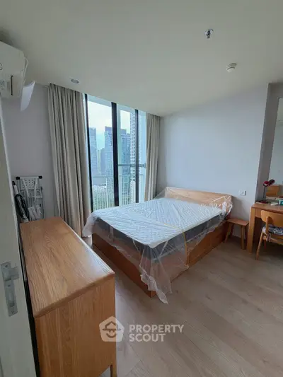 Modern bedroom with city view, featuring wooden furniture and large windows.