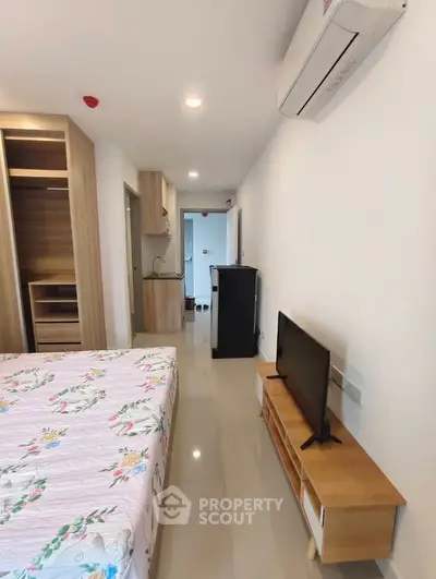 Modern bedroom with air conditioning, TV, and compact kitchenette in a stylish apartment.