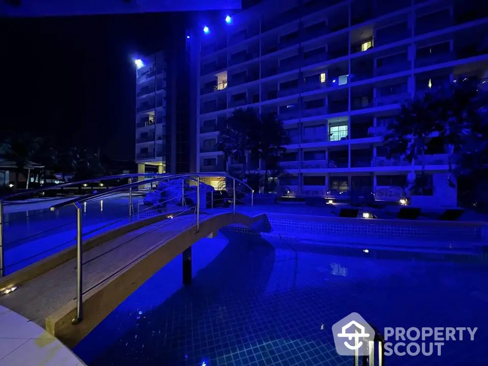 Luxurious night view of a modern apartment complex with illuminated pool and bridge