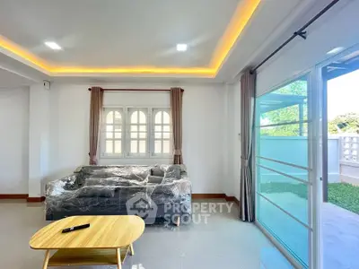 Spacious living room with modern sofa and large windows offering natural light and garden view.