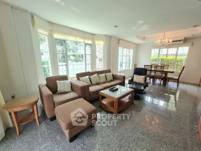 Spacious living room with elegant furniture and large windows offering garden views