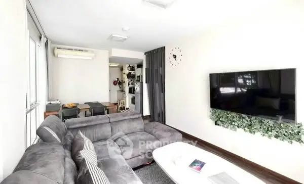 Modern living room with sleek decor and wall-mounted TV in a bright apartment.