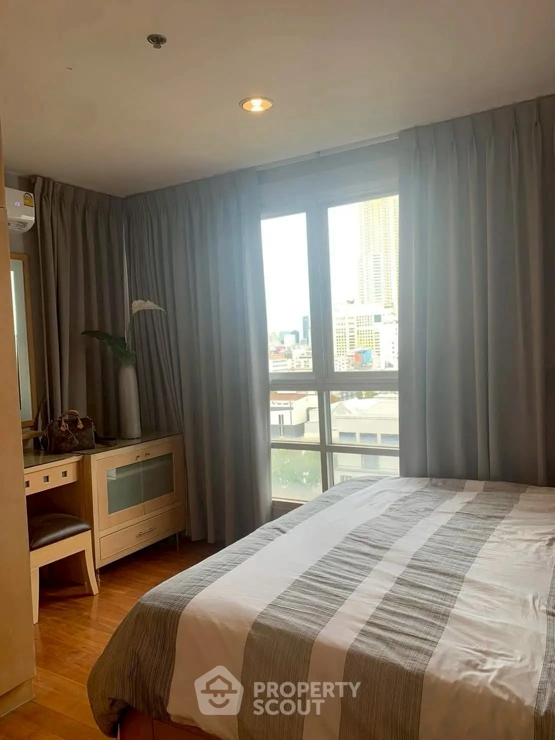 Cozy bedroom with city view, featuring a comfortable bed and elegant curtains.