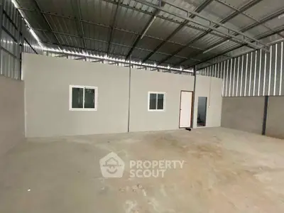 Spacious industrial warehouse with metal roof and concrete floor, ideal for storage or workshop use.