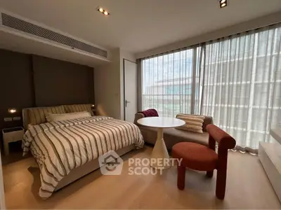 Modern bedroom with stylish furniture and large windows offering natural light.