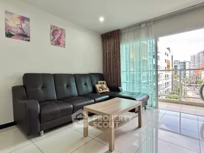 Modern living room with sleek leather sofa and large balcony offering city views.