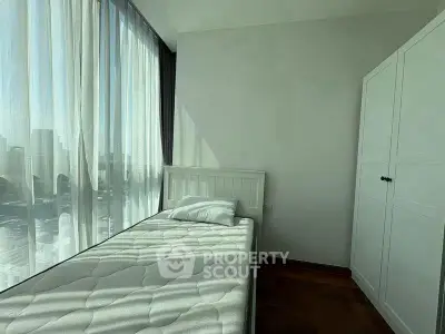 Bright minimalist bedroom with large windows and simple furnishings