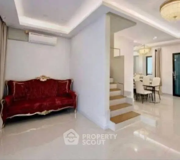 Luxurious living room with elegant red sofa and modern dining area, perfect for sophisticated living.