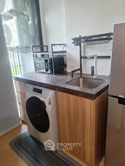 Modern kitchen with washing machine and sleek countertop in compact layout