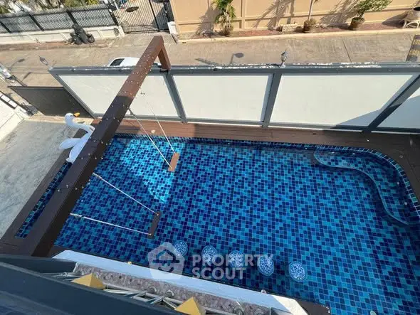 Stunning aerial view of a modern swimming pool with unique swing feature and vibrant blue tiles.