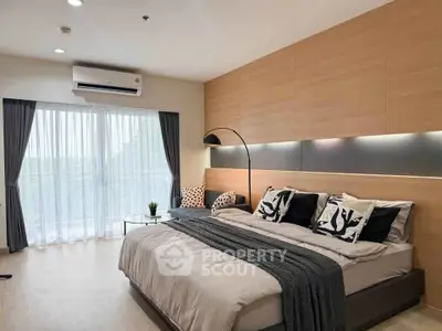 Modern bedroom with stylish decor and large window offering natural light.