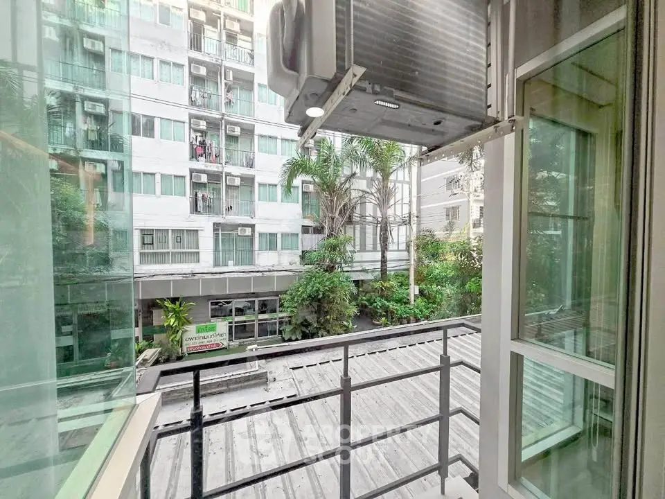 Charming balcony view overlooking lush greenery and modern building facade, perfect for urban living.