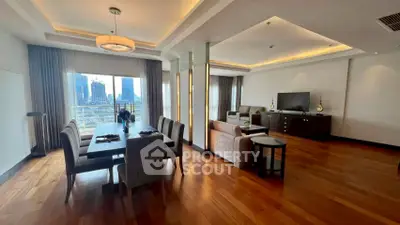 Luxurious open-plan living and dining area with city view, elegant decor, and hardwood floors.