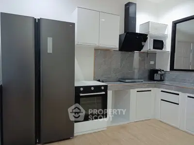 Modern kitchen with sleek appliances and open layout, featuring a large fridge and built-in oven.