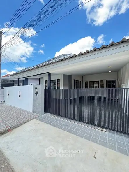 Modern single-story house with sleek gate and driveway under a clear blue sky.