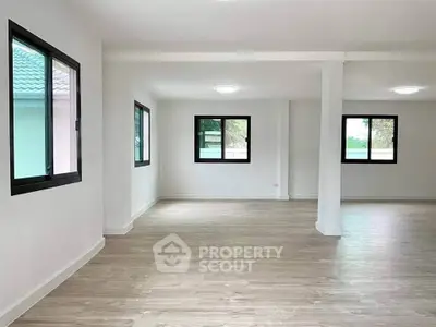 Spacious open-plan living area with large windows and wooden flooring