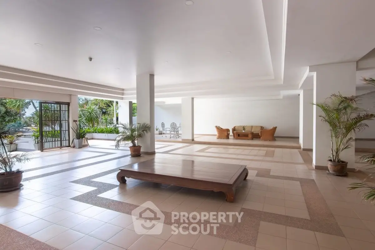 Spacious open-air lobby with elegant seating and lush greenery, perfect for relaxation and social gatherings.