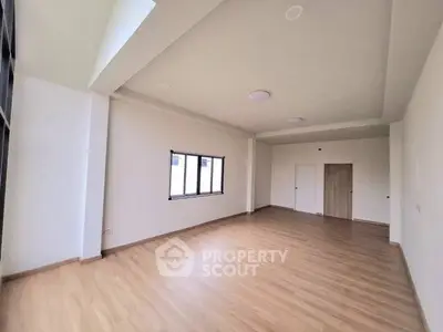 Spacious empty room with wooden flooring and large windows, ideal for customization.