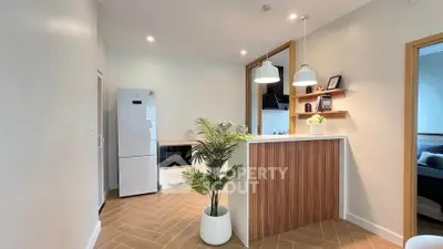 Modern kitchen with sleek design, featuring white appliances and stylish lighting.