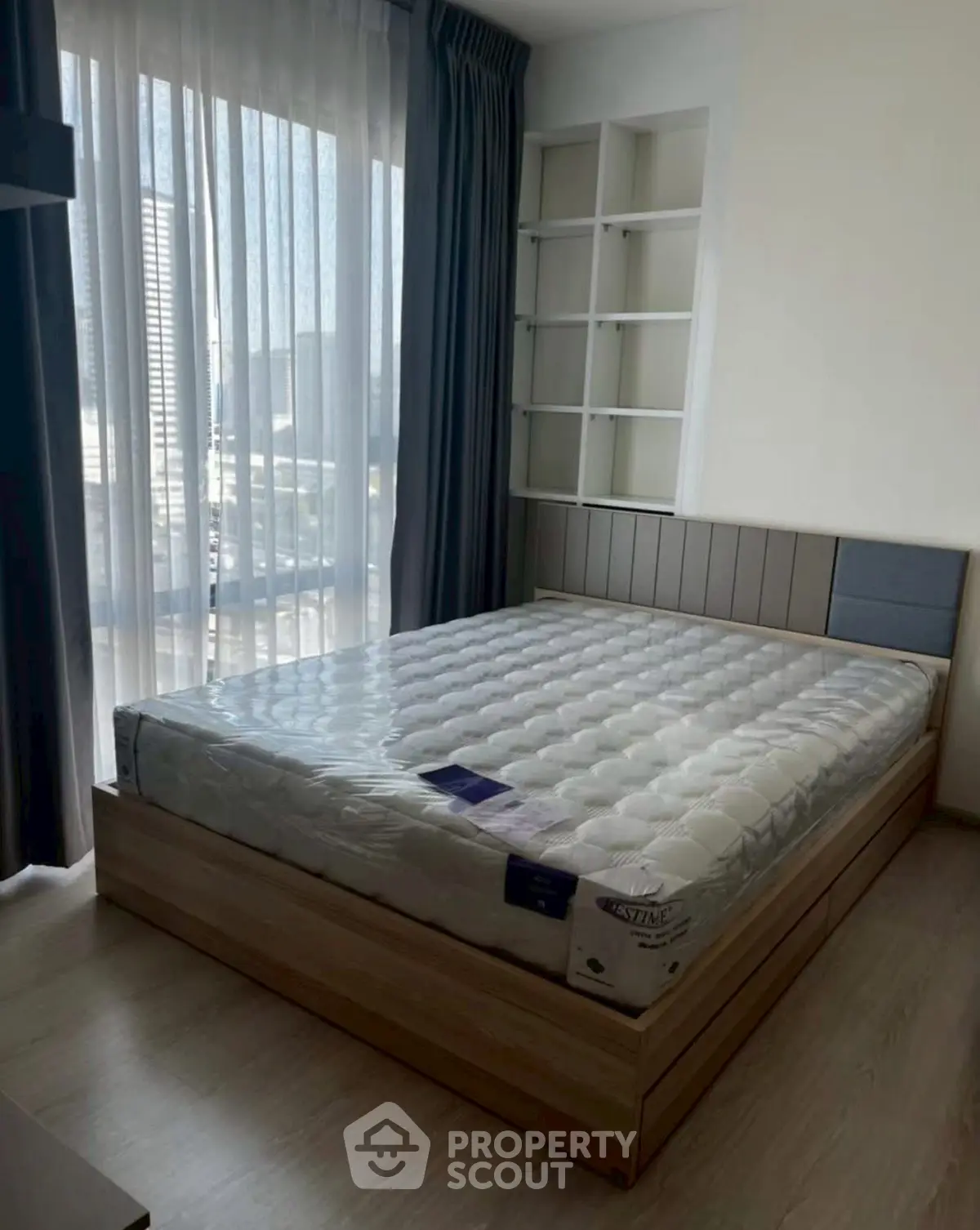 Modern bedroom with large window and stylish bed frame in a bright apartment.