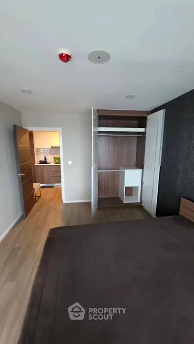 Modern bedroom with open wardrobe and view into stylish kitchen