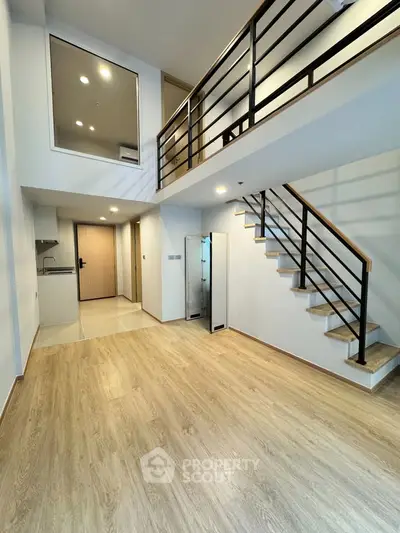 Modern duplex apartment with sleek staircase and open layout, featuring high ceilings and wooden flooring.