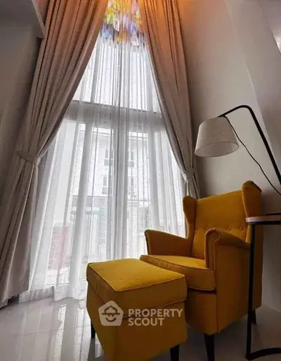 Elegant living room with high ceiling and yellow armchair by large window.