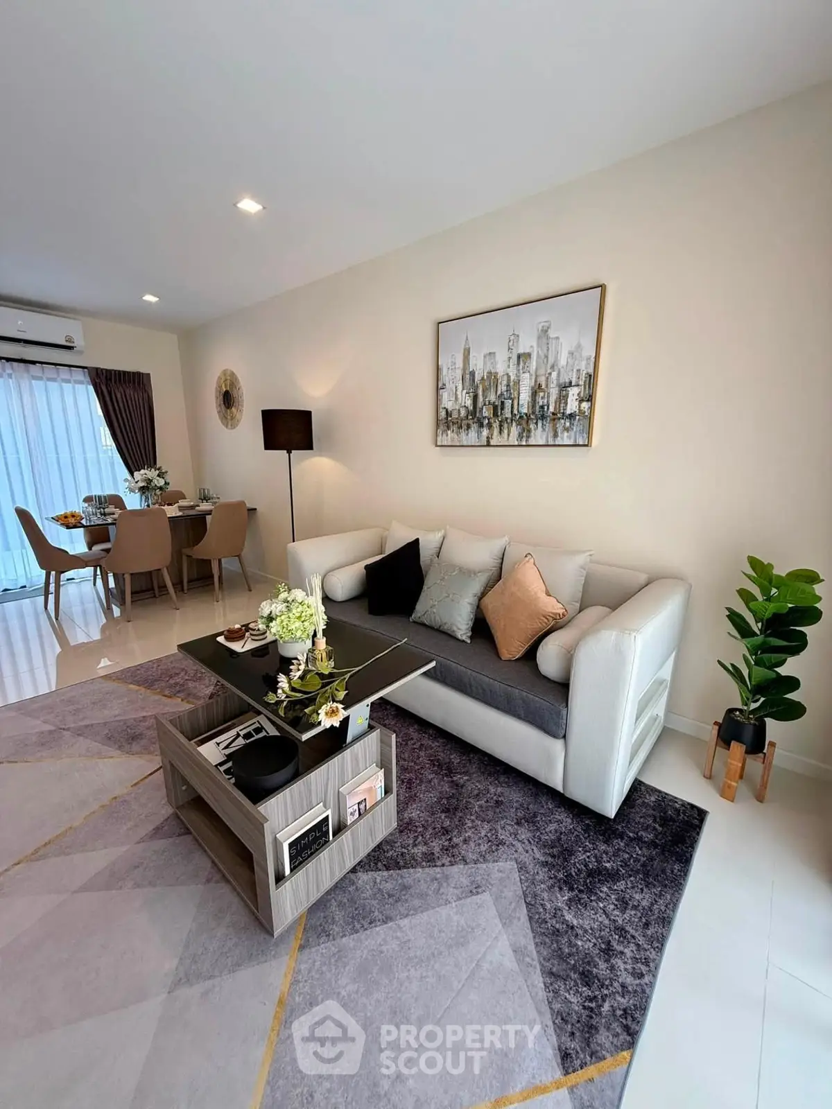 Modern living room with stylish decor and open dining area, featuring elegant furniture and contemporary artwork.
