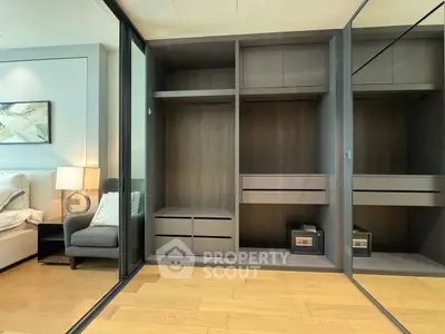 Spacious modern bedroom with built-in wardrobe and cozy seating area, perfect for stylish living.