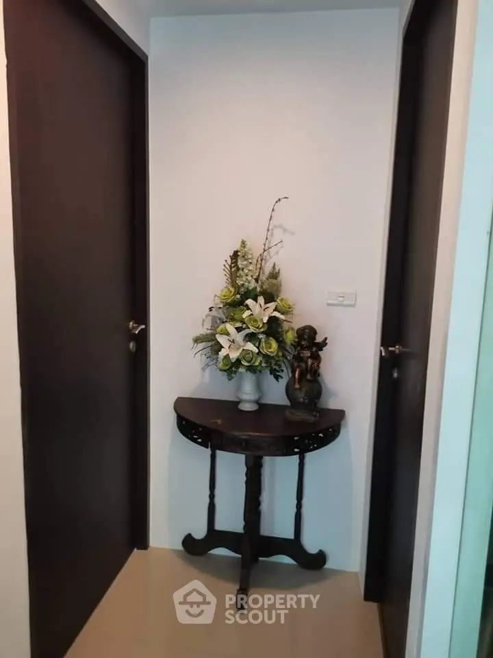 Charming hallway with elegant floral arrangement on antique table between two doors.