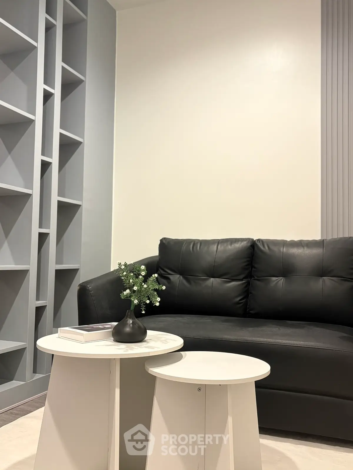 Modern living room with sleek black sofa and stylish white tables, perfect for contemporary urban living.