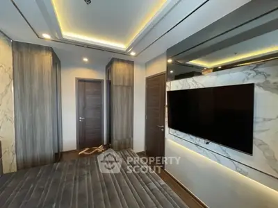 Modern bedroom with sleek design and large wall-mounted TV