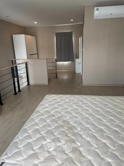 Spacious bedroom with modern design and natural light, featuring a comfortable mattress and sleek air conditioning unit.