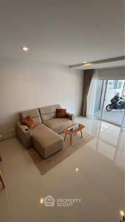 Modern living room with cozy beige sofa and natural light from large windows.