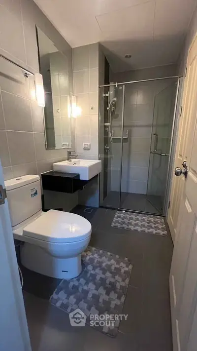Modern bathroom with glass shower and sleek fixtures in contemporary apartment.