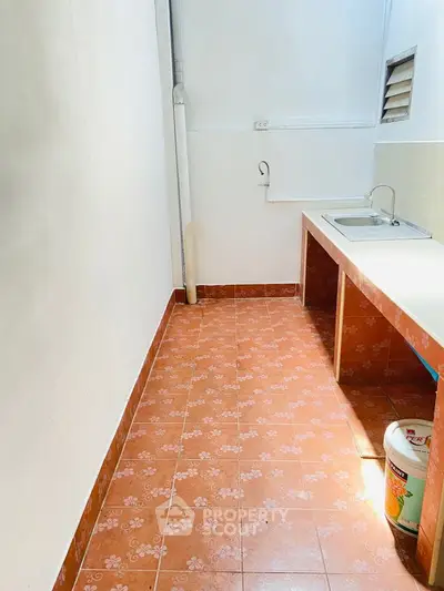 Compact kitchen area with tiled floor and basic sink setup