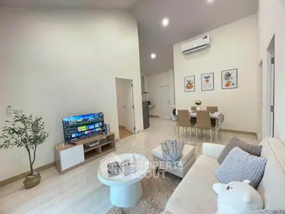 Modern living room with cozy decor and open dining area, featuring stylish furniture and wall art.
