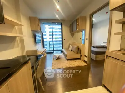 Modern apartment interior with open living room and bedroom view, featuring stylish furniture and large windows.