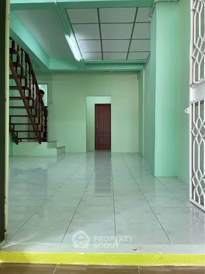 Spacious interior with tiled floor and staircase, ideal for customization.