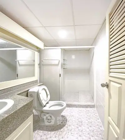 Spacious bathroom with modern fixtures and walk-in shower in a bright, tiled setting.