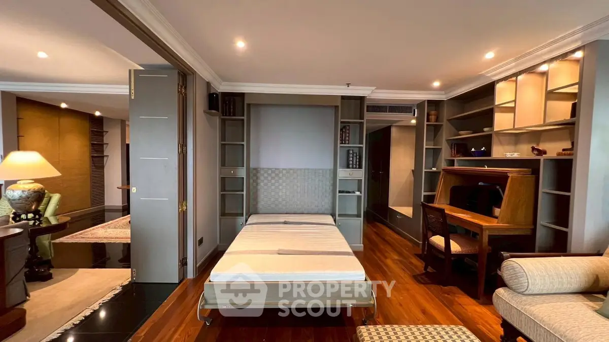 Luxurious living room with elegant decor and built-in shelving, featuring a cozy workspace and stylish lighting.