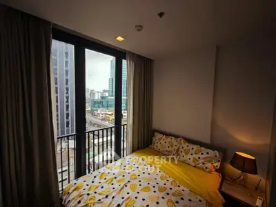 Cozy bedroom with city view, featuring modern decor and large windows for natural light.