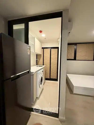 Modern compact apartment with kitchen and washing machine, featuring sleek design and efficient use of space.