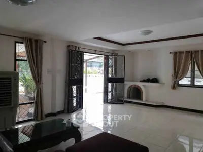 Spacious living room with open doors to patio, featuring elegant curtains and a cozy fireplace.