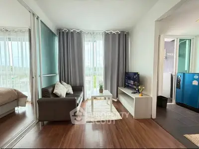 Modern living room with sleek furniture and natural light, adjacent to a cozy bedroom and stylish kitchen.
