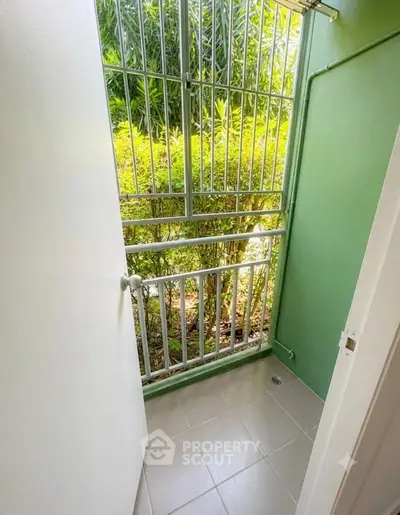Charming small balcony with lush greenery view, perfect for relaxation and fresh air.