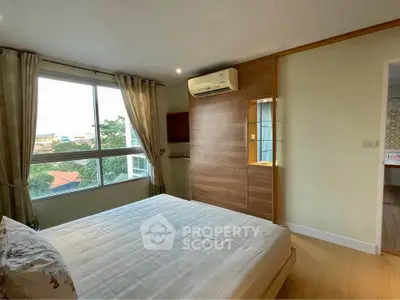 Bright bedroom with large window and modern air conditioning unit.