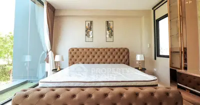 Luxurious bedroom with tufted bed and large windows offering natural light and garden view.