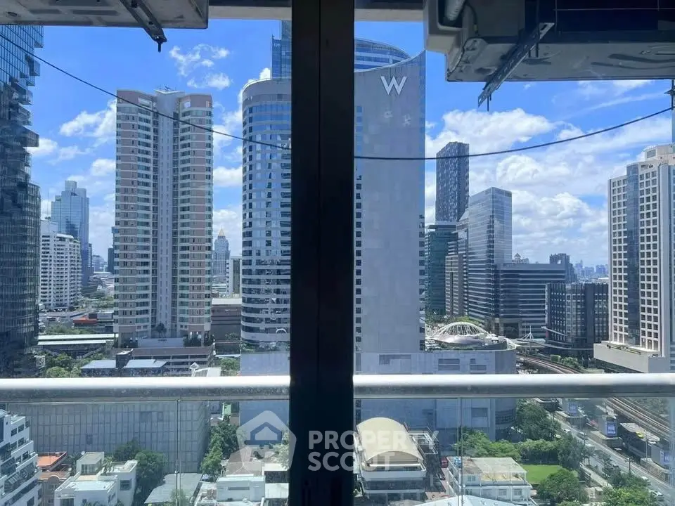 Stunning cityscape view from a high-rise balcony with modern skyscrapers under a clear blue sky.